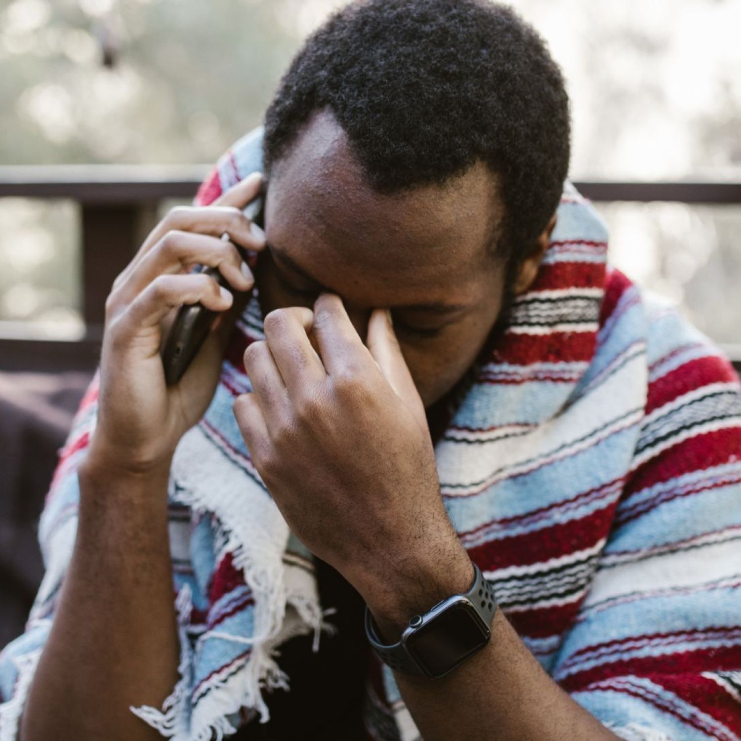 Homem preto falando ao telefone com semblante preocupado